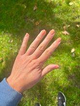 Load image into Gallery viewer, Hand with painted nails against a grassy background