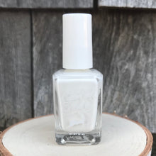 Load image into Gallery viewer, A bottle of white nail polish on a wooden display with a natural wood background.